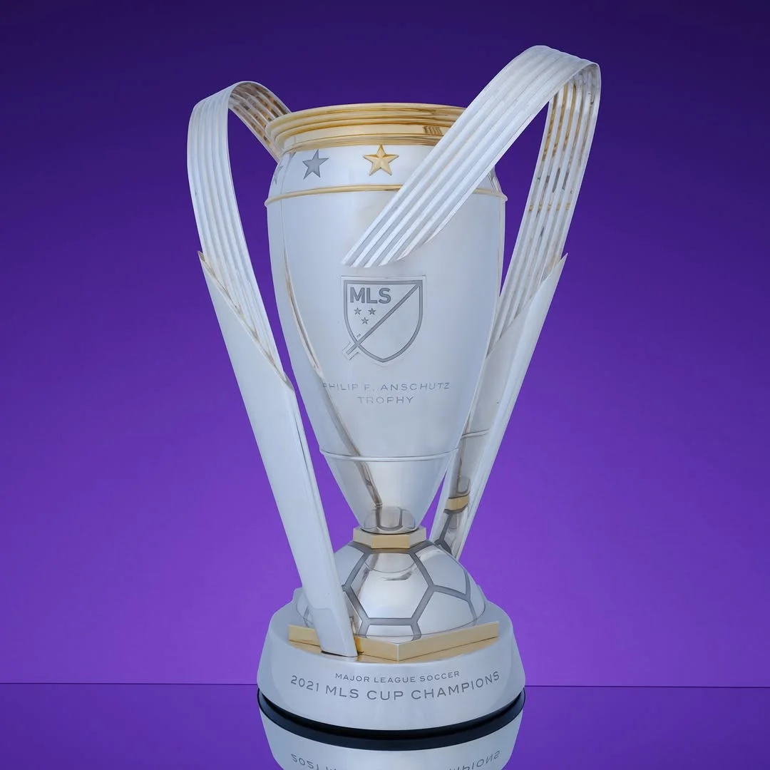 The silver and gold The Philip F. Anschutz Trophy on a purple background.