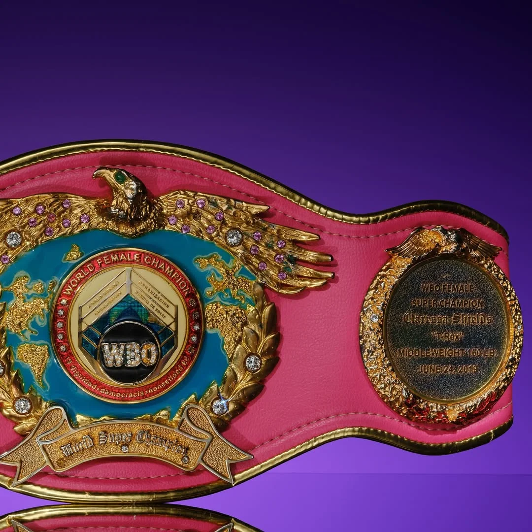 Pink and gold WBO Middleweight Championship belt, inscribed with “T-Rex,” her nickname on a purple background.