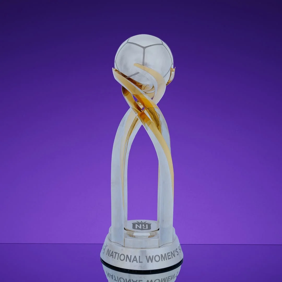 Silver and gold National Women’s Soccer League Trophy on a purple background.