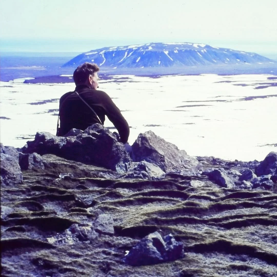 A photo of a person sitting overlooking a glacier in Iceland.